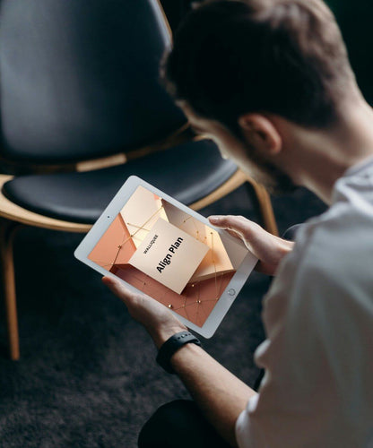 Person holding a tablet with a 'Align Plan' SMM guide on it, sitting in a chair.
