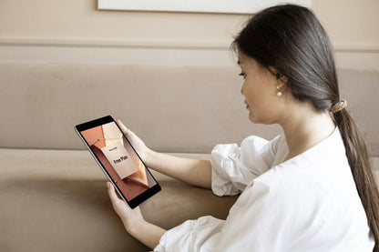 Woman using a tablet with 'Free Plan' SMM guide in a cozy living room setting