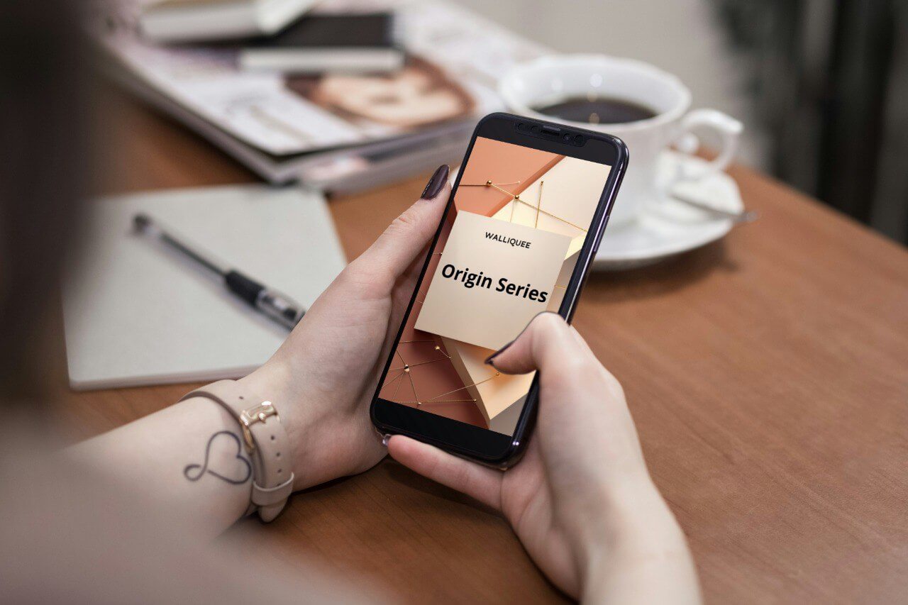 Person holding a smartphone with a SMM guide 'Origin Series'  display on a wooden table.